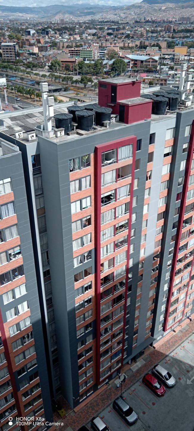 Torre con acabado gris y franjas rojas frente al perfil de la ciudad