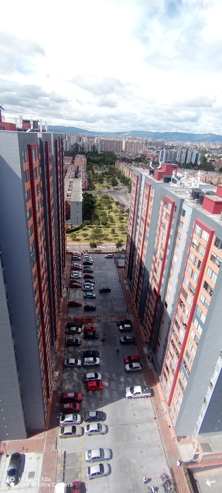 Torre en acabado gris junto a zona verde y vía perimetral