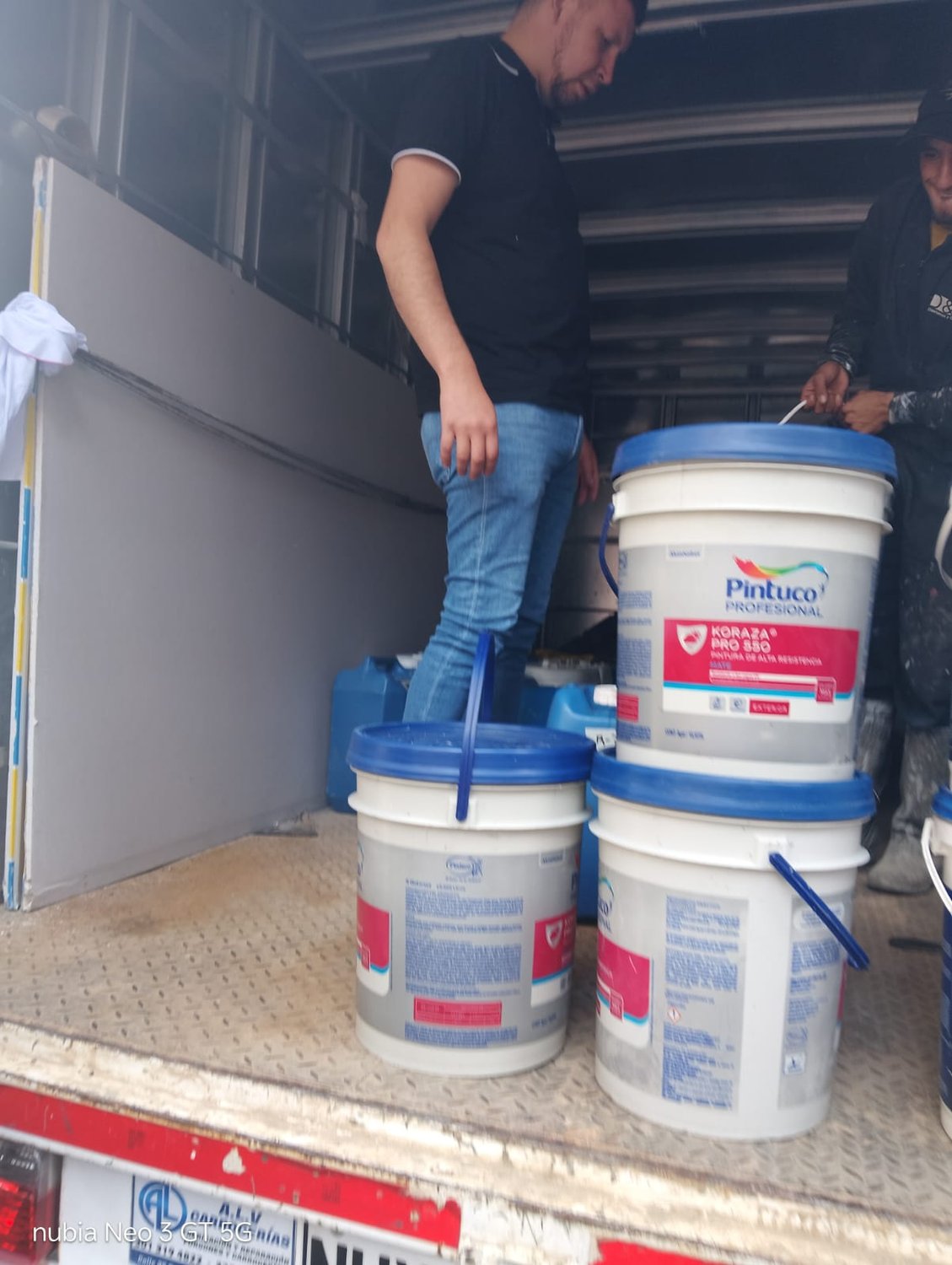 Descargue de canecas de pintura desde el camión en la obra