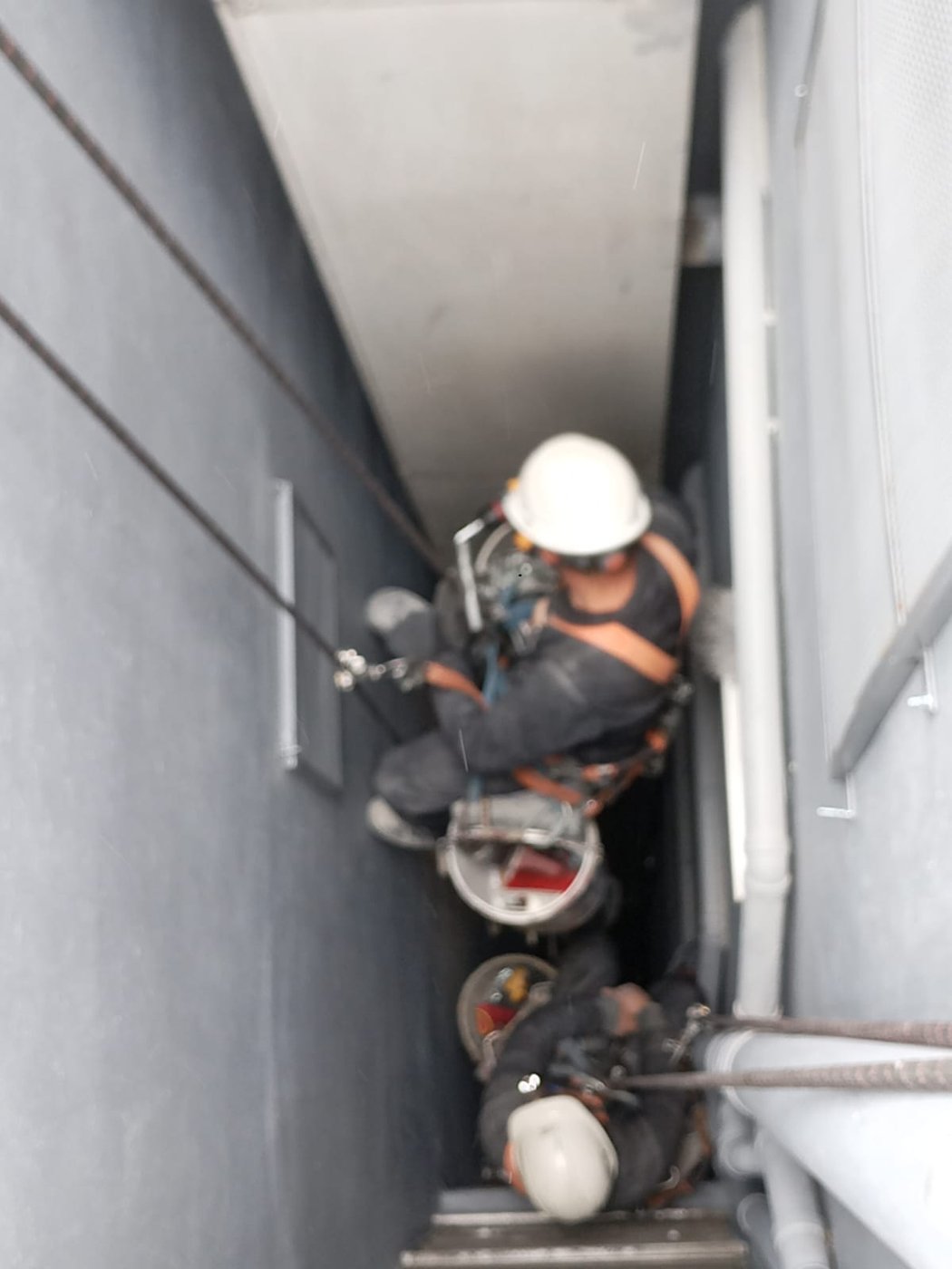 Operario suspendido trabajando dentro del ducto de ventilación