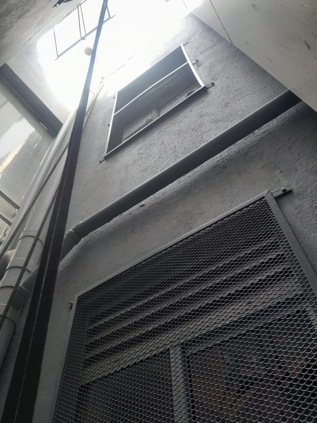 Rejilla grande instalada en el muro del ducto, vista desde abajo hacia el piso superior